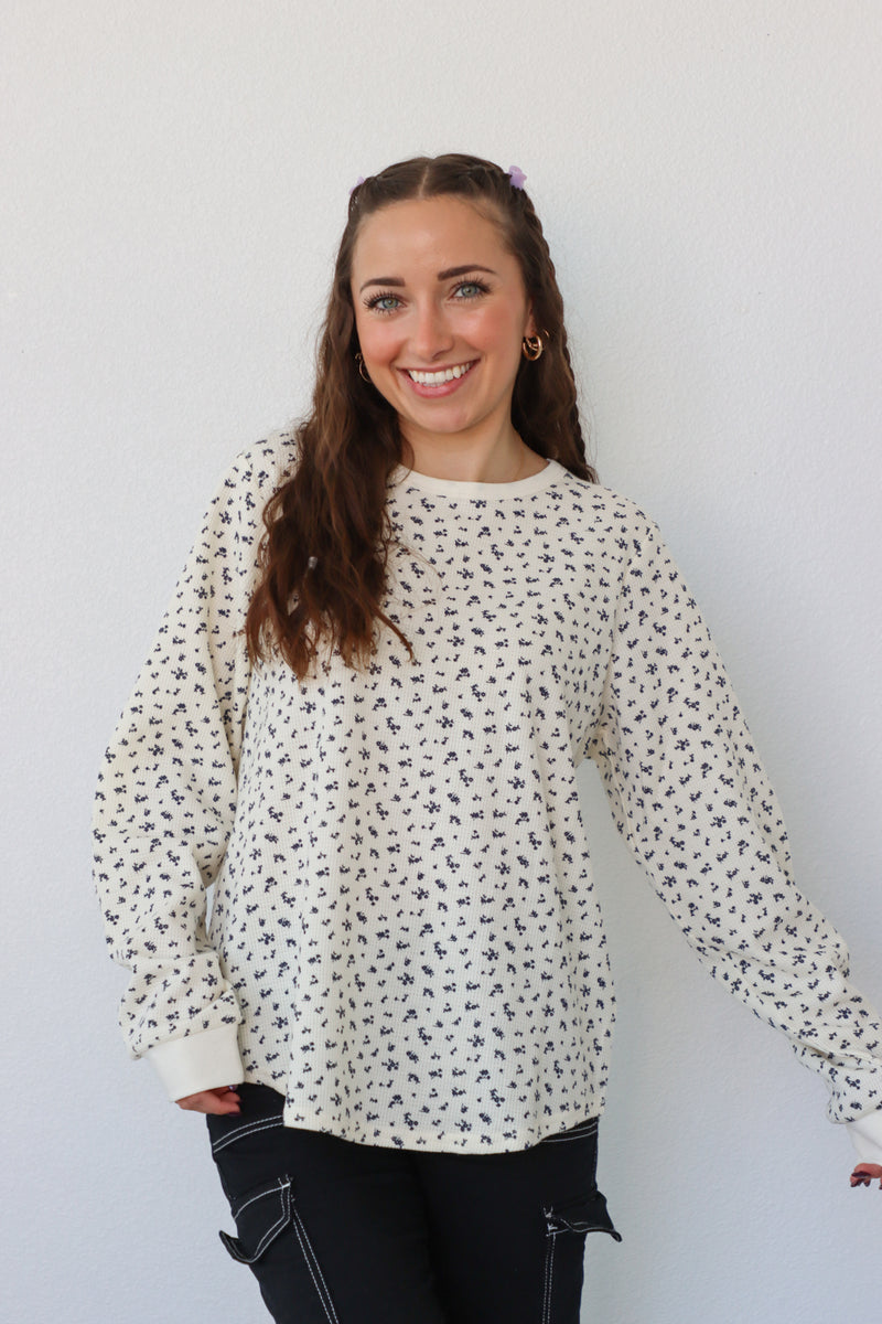 girl wearing cream long sleeve top with floral pattern