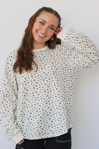 girl wearing cream long sleeve top with floral pattern