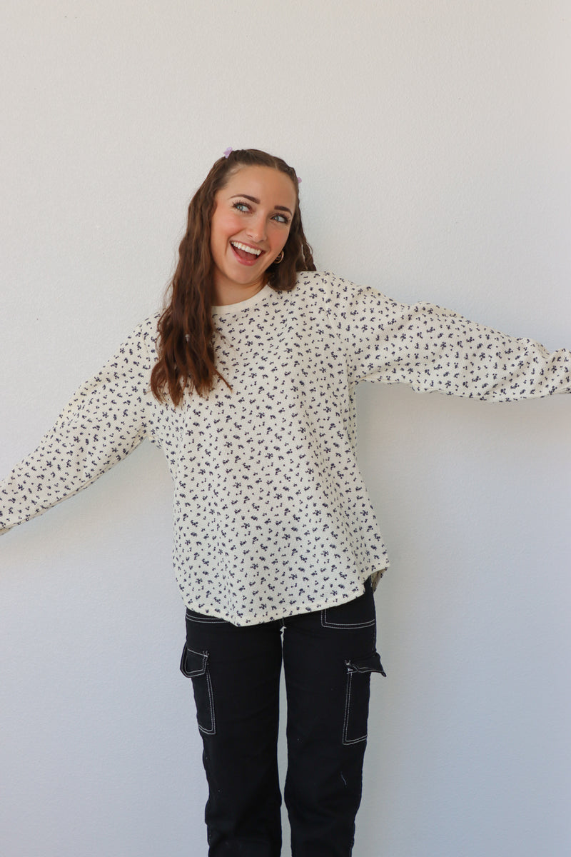 girl wearing cream long sleeve top with floral pattern