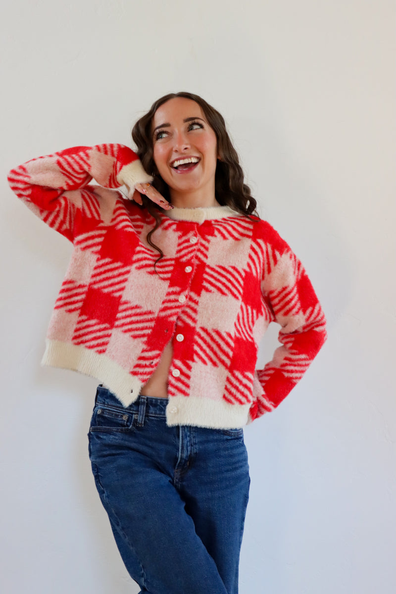 Woman wearing a red and white checkered sweater against a plain background