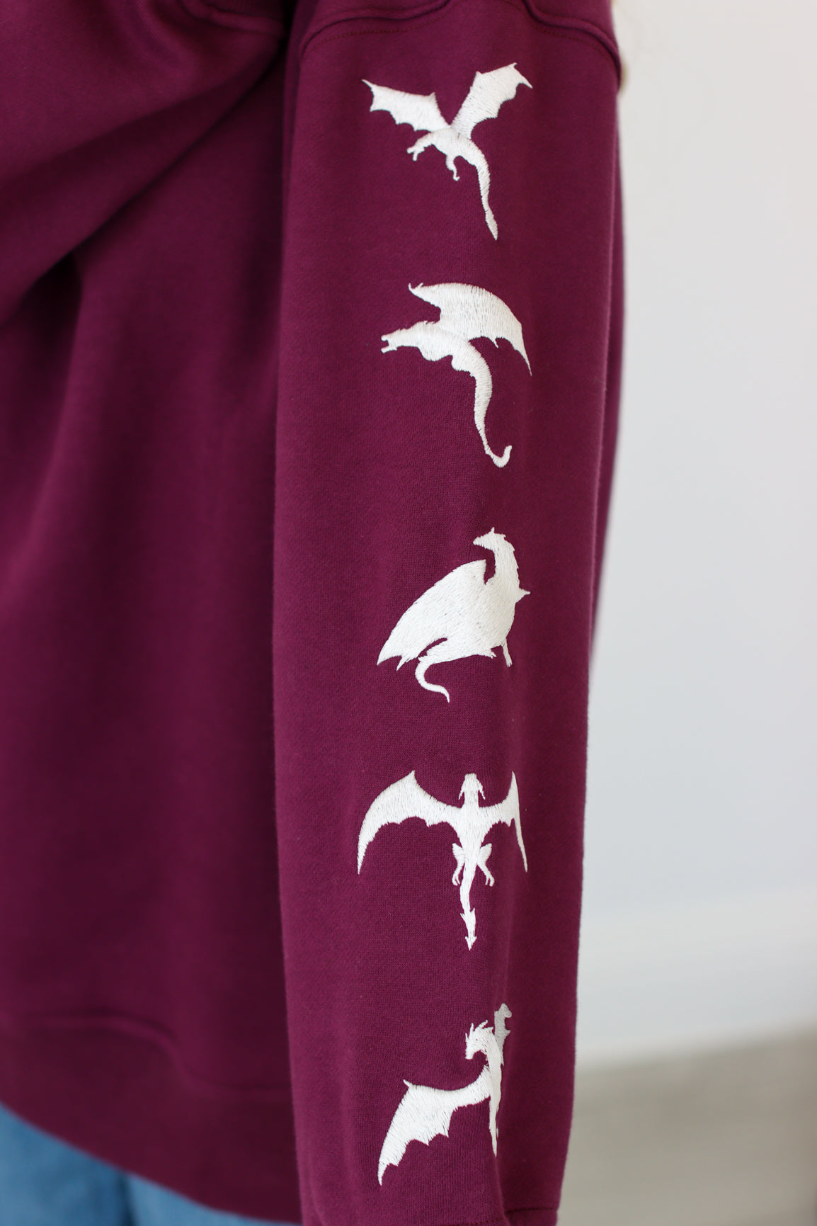 Purple fabric with white dragon embroidery design on a plain background