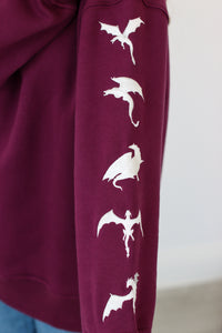 Purple fabric with white dragon embroidery design on a plain background