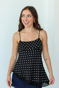 Woman wearing a black polka dot top against a white background