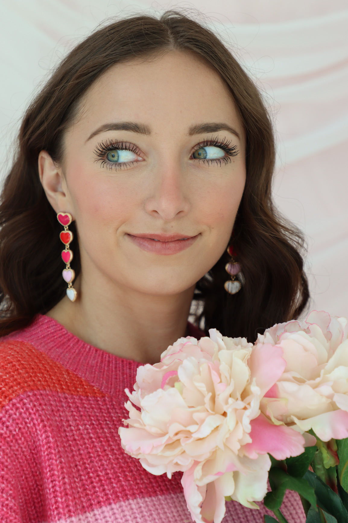 girl wearing red, pink, and white heart shaped drop earrings