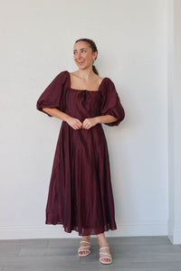 girl wearing long dark purple dress with 3/4 puff sleeves