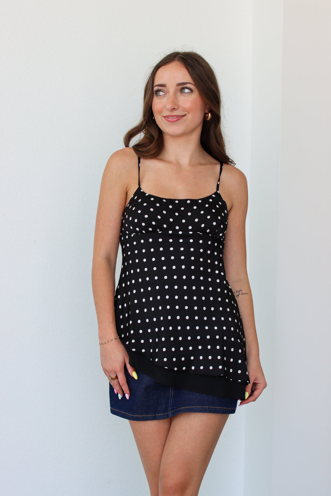 Woman wearing a black polka dot top with a denim mini skort 