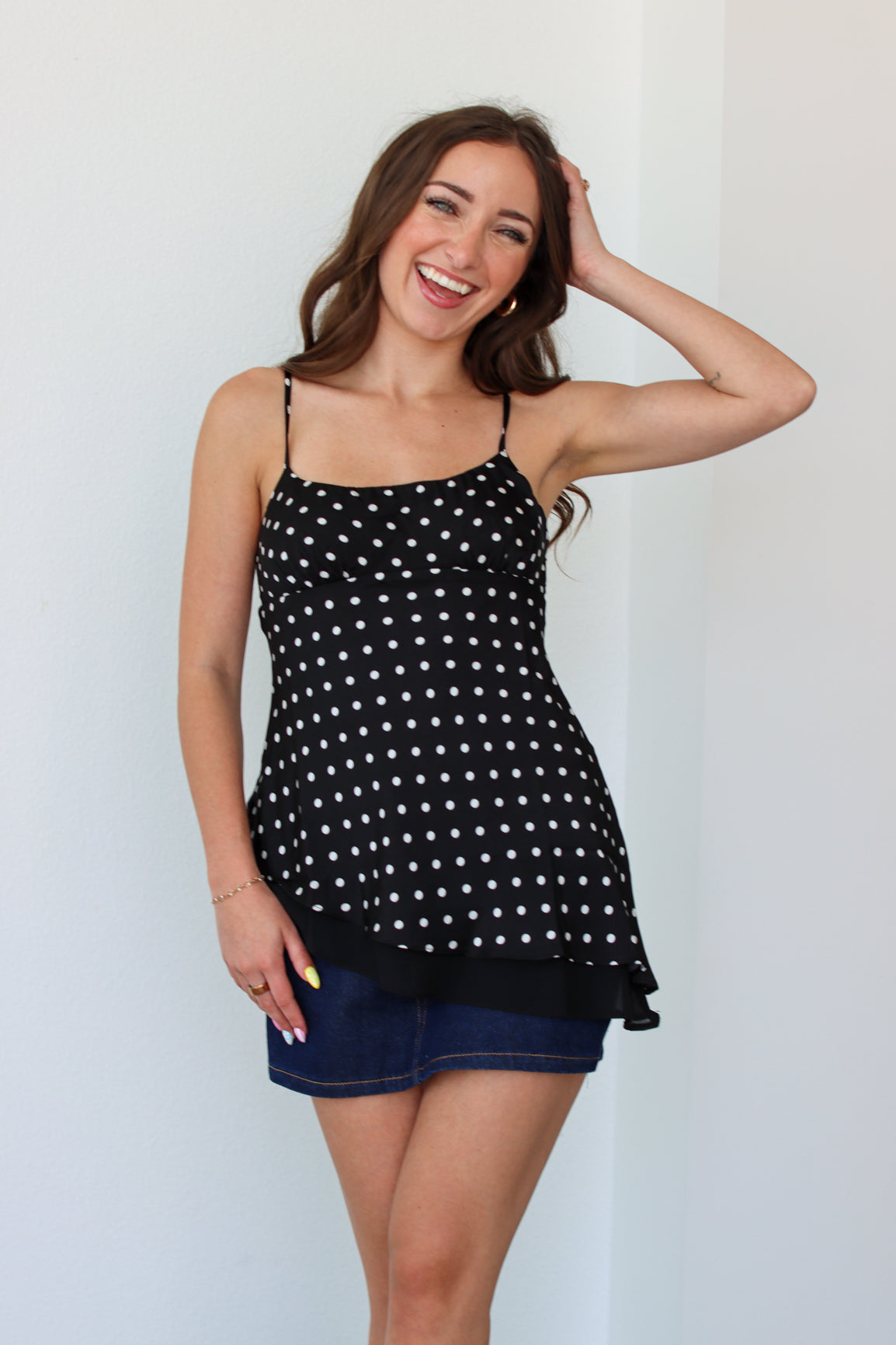 Woman wearing a black polka dot top with a denim mini skort 