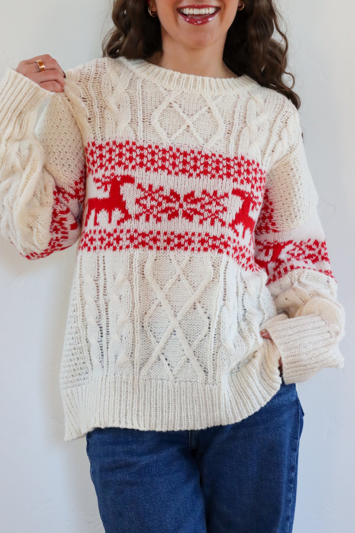 Person wearing a cream sweater with red deer pattern against a white background