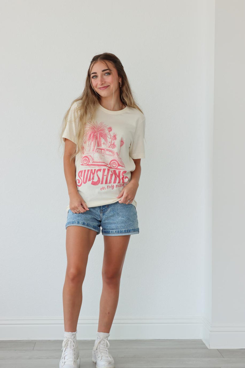 girl wearing cream t-shirt with pink "sunshine on my mind" graphic