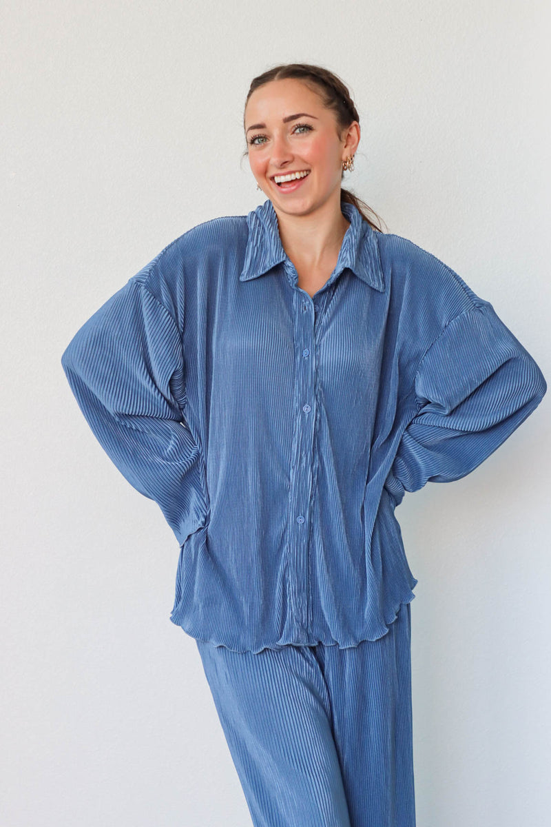 girl wearing denim blue outfit set with long sleeve button down blouse and elastic waist palazzo pants. Both in a pleated crinkle fabric