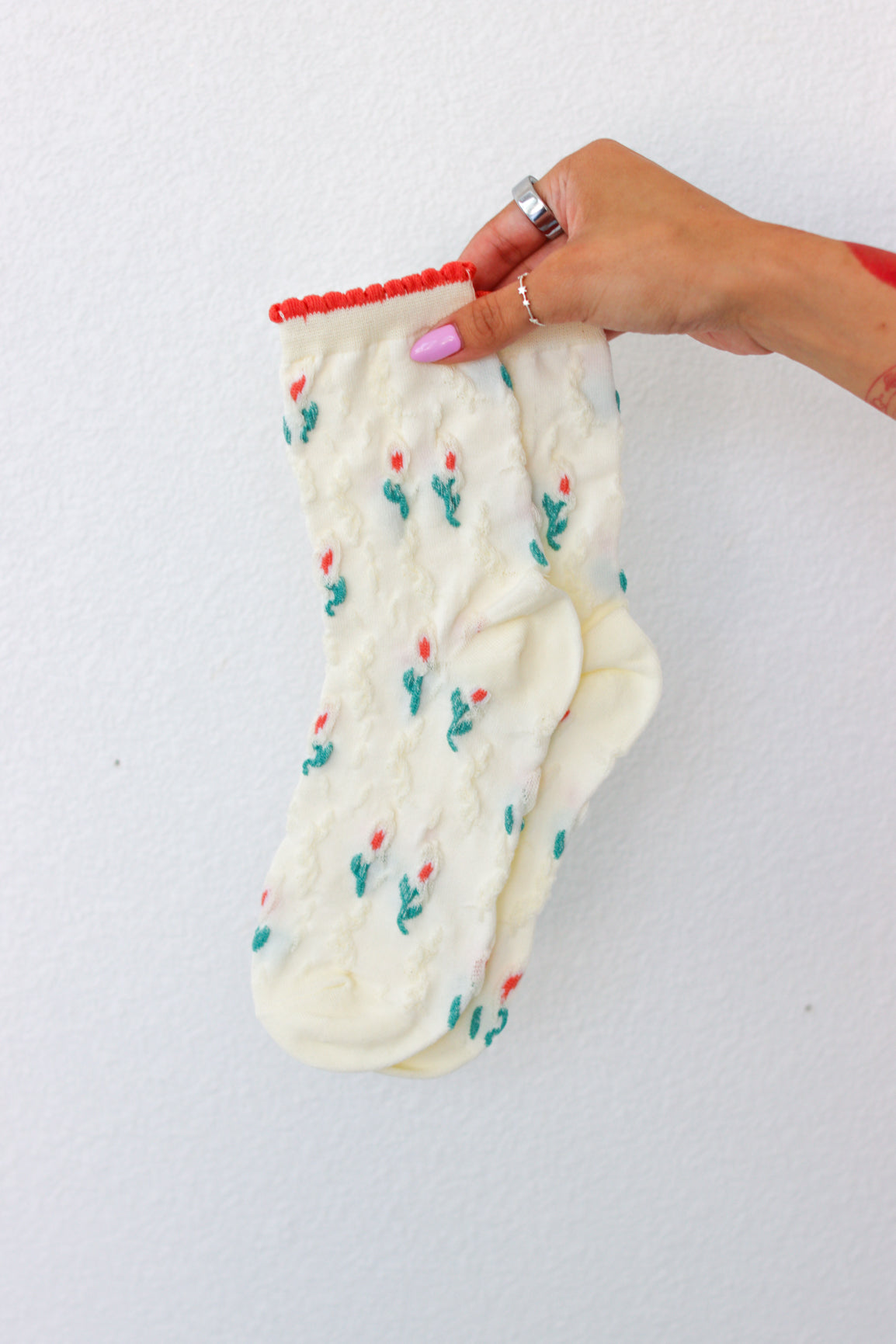 White sock with flower pattern held by a hand on a white background