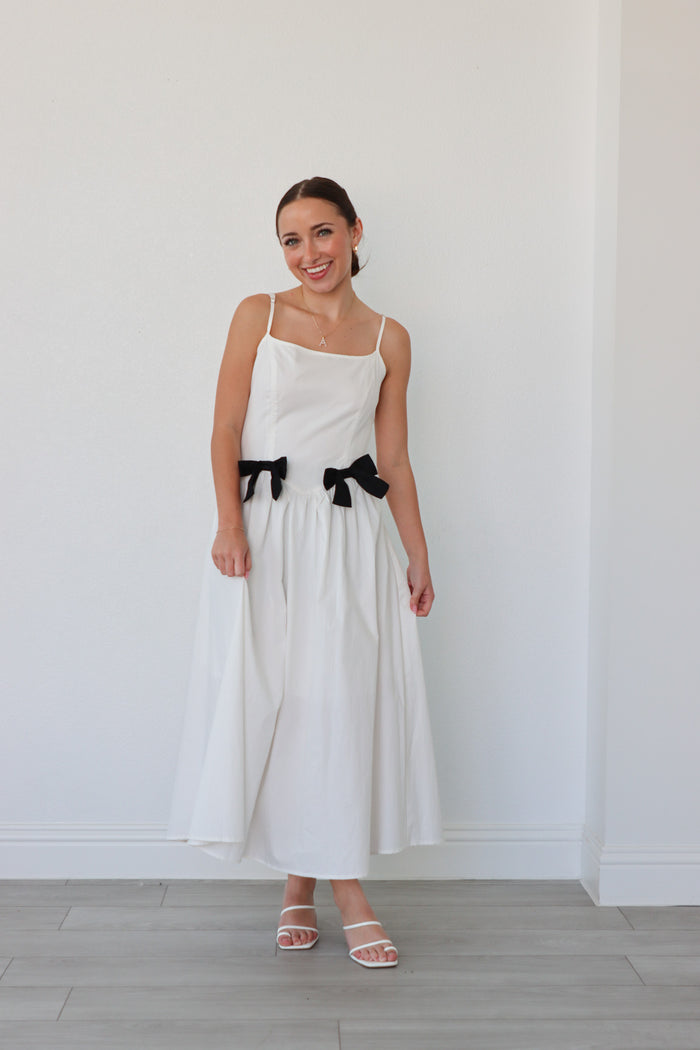 girl wearing white long dress with black bow details