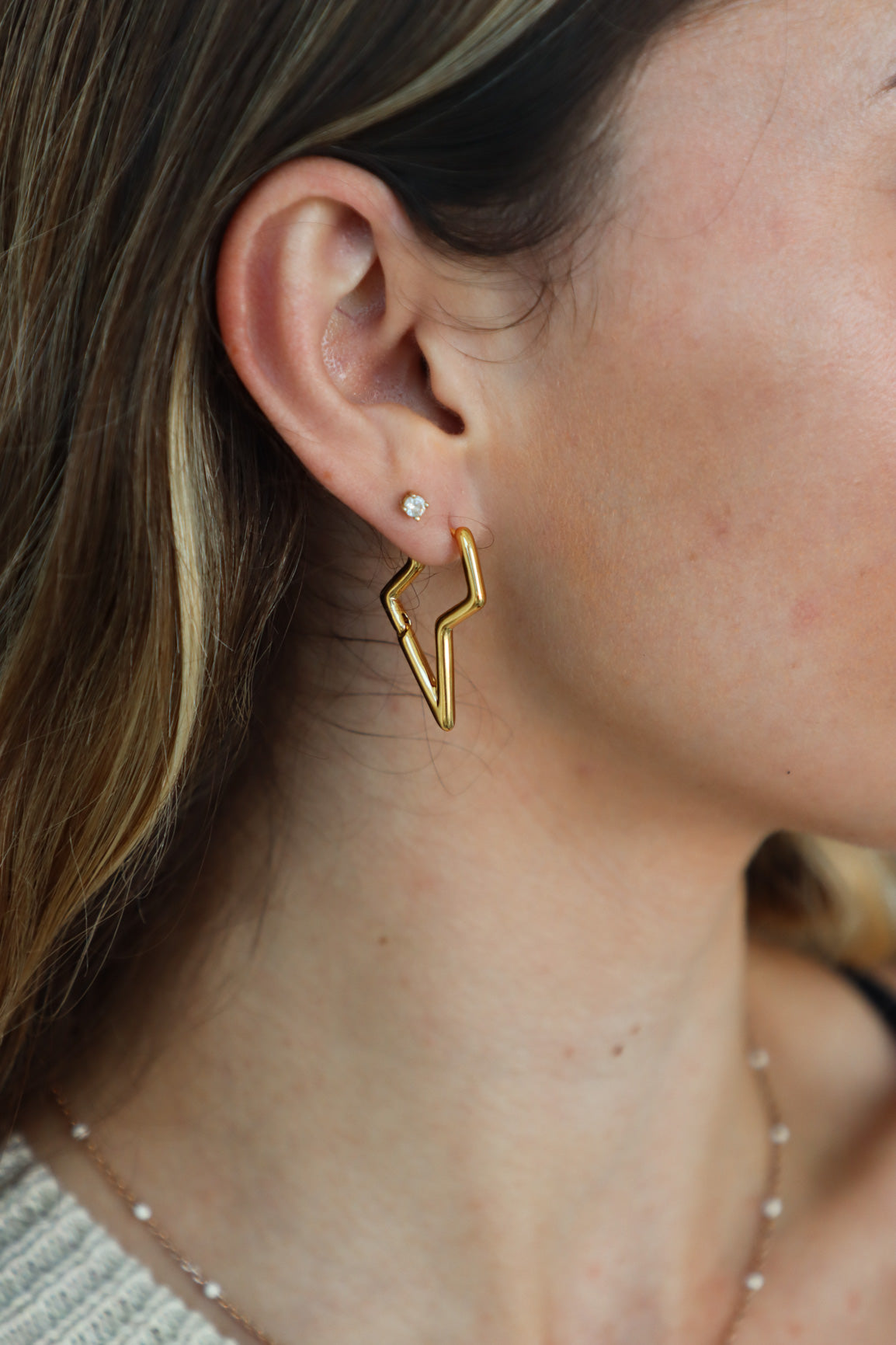 girl wearing gold lightning bolt earrings