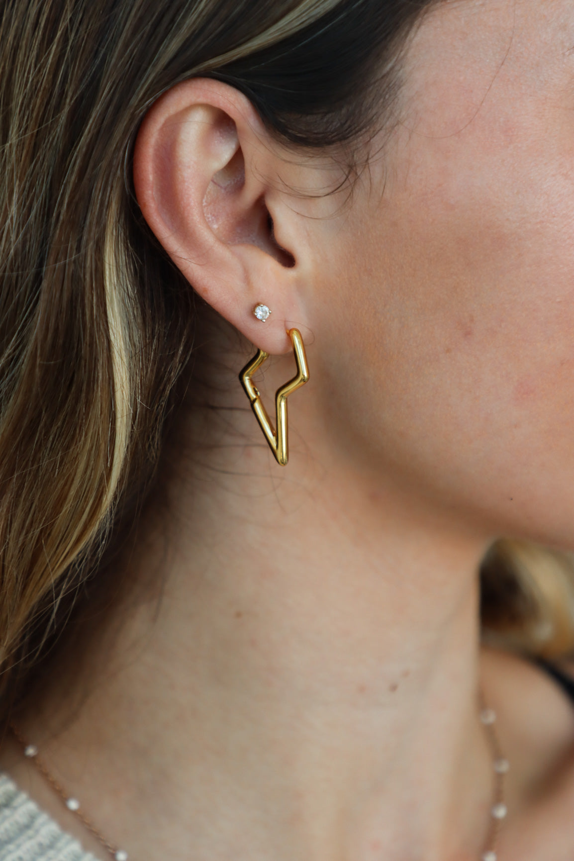 girl wearing gold lightning bolt earrings