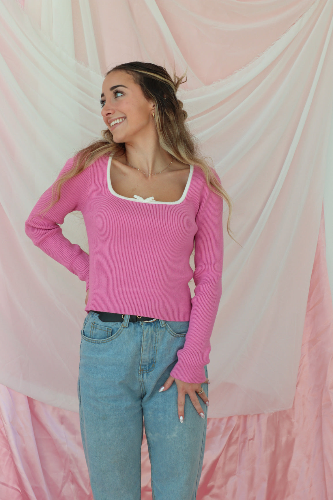 girl wearing pink long sleeved ribbed top with white trim and white bow detailing