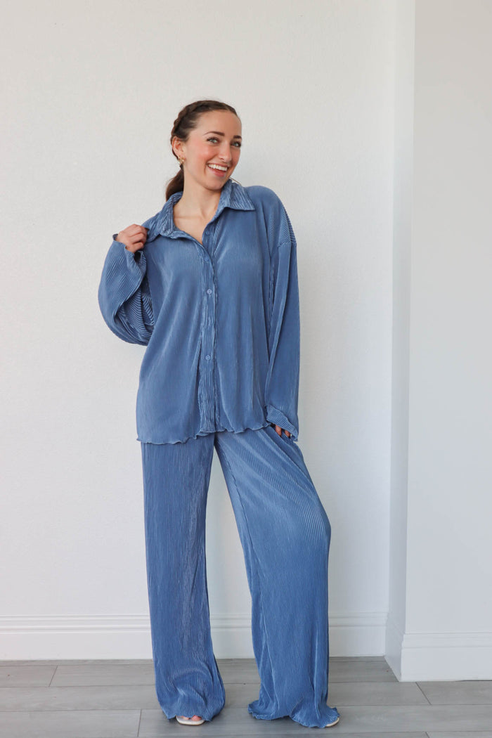 girl wearing denim blue outfit set with long sleeve button down blouse and elastic waist palazzo pants. Both in a pleated crinkle fabric