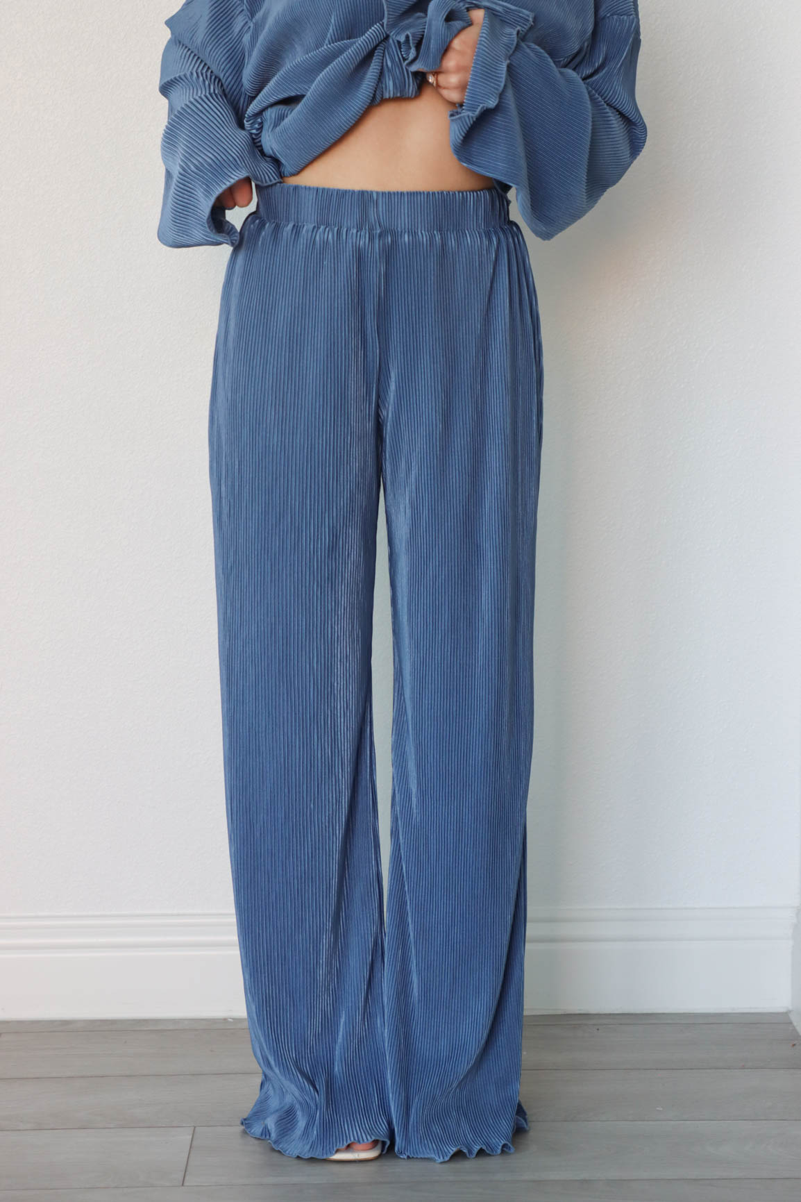 girl wearing denim blue outfit set with long sleeve button down blouse and elastic waist palazzo pants. Both in a pleated crinkle fabric