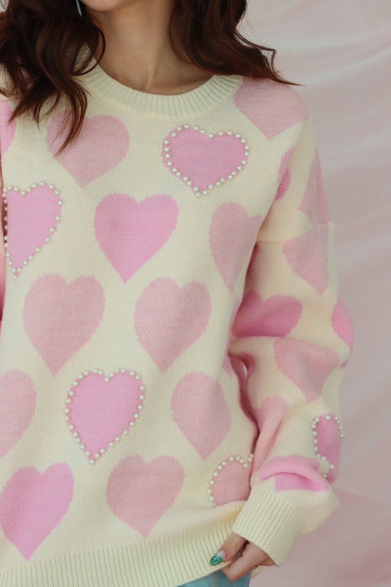 girl wearing cream sweater with light pink hearts and pearl detailing