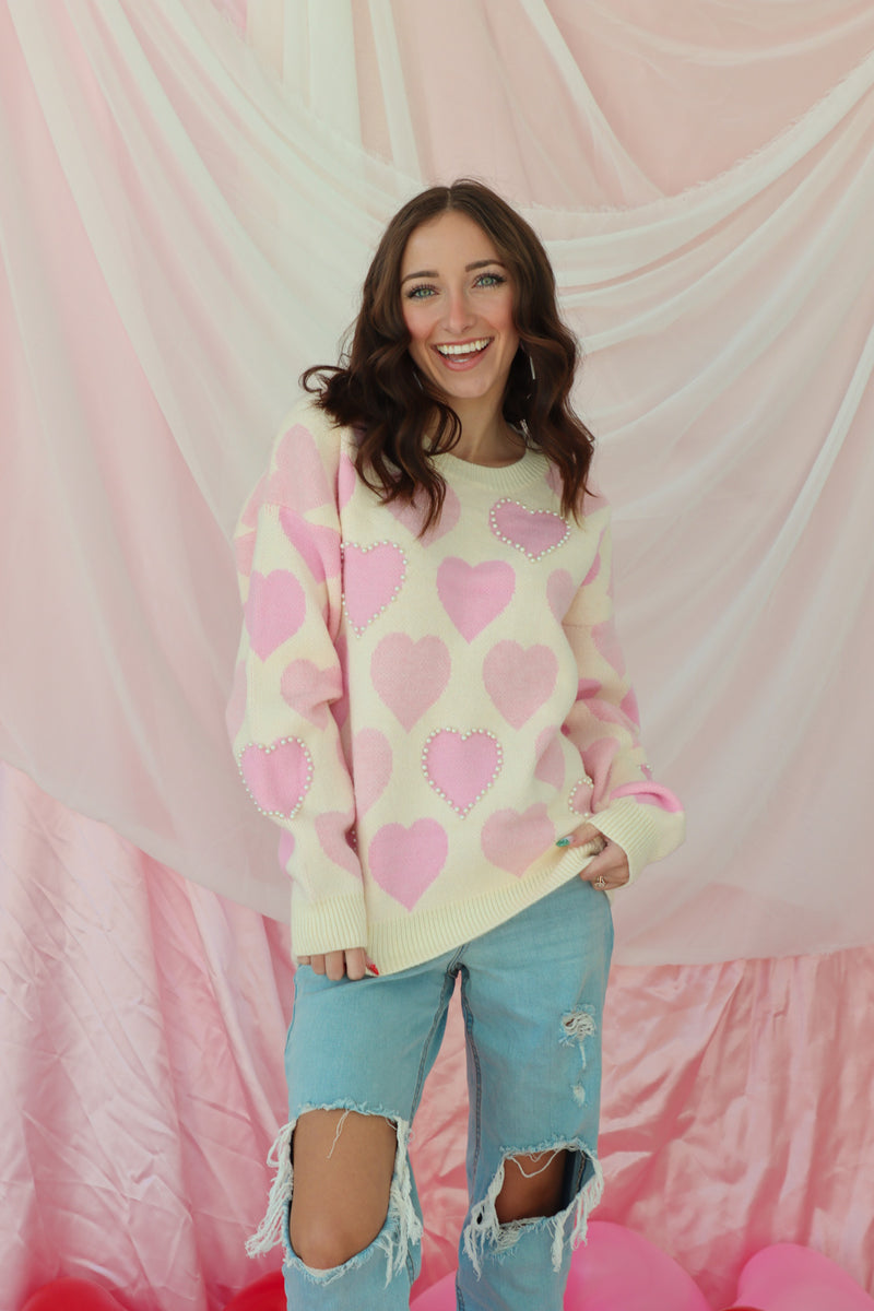 girl wearing cream sweater with light pink hearts and pearl detailing