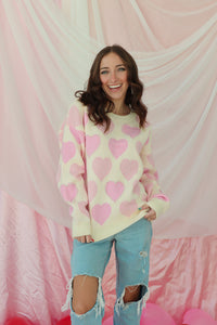 girl wearing cream sweater with light pink hearts and pearl detailing