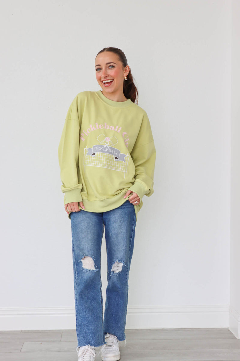 girl wearing lime green crewneck sweatshirt with embroidered pickle ball graphic