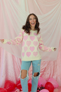 girl wearing cream sweater with light pink hearts and pearl detailing