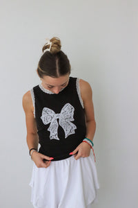 girl wearing black tank top with white lace trim & bow detailing