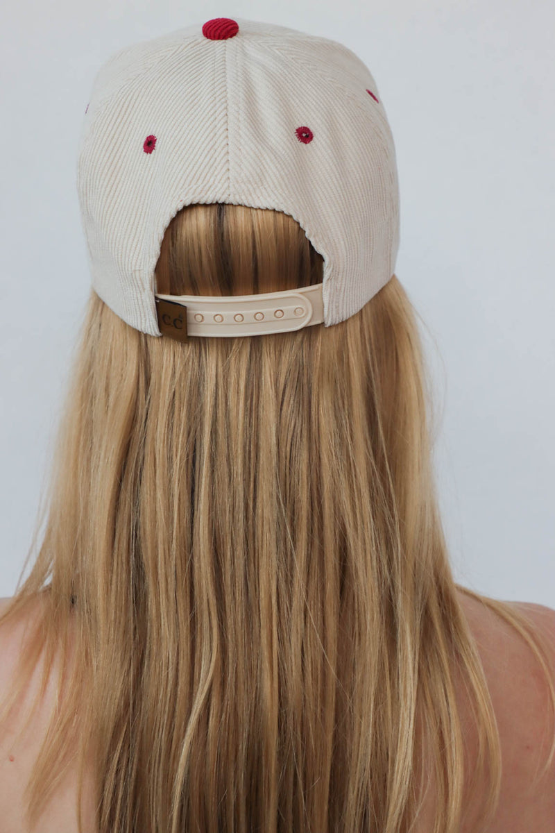 girl wearing cream & red "darlin'" hat