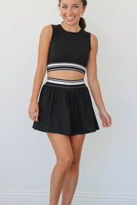 girl wearing black and white athletic set: tank top and skirt