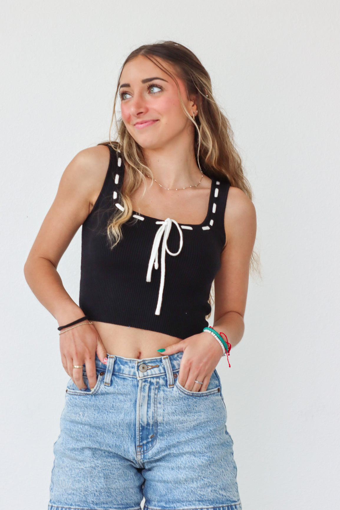 girl wearing black knit tank top with white stitch and tie detailing