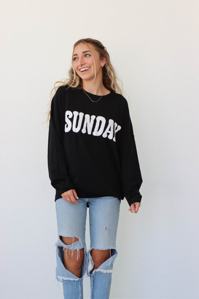 girl wearing black sweater with white "sunday" graphic