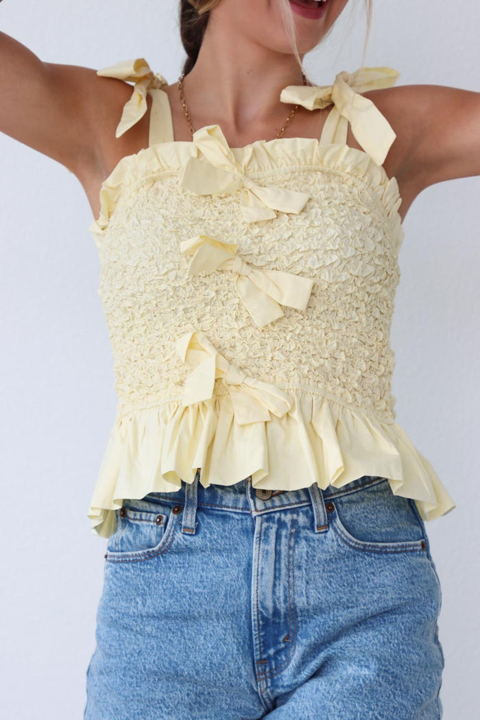 girl wearing yellow tank top with bow detailing