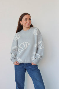 girl wearing light blue croissant and coffee sweater