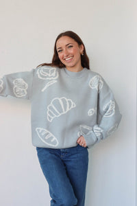 girl wearing light blue croissant and coffee sweater