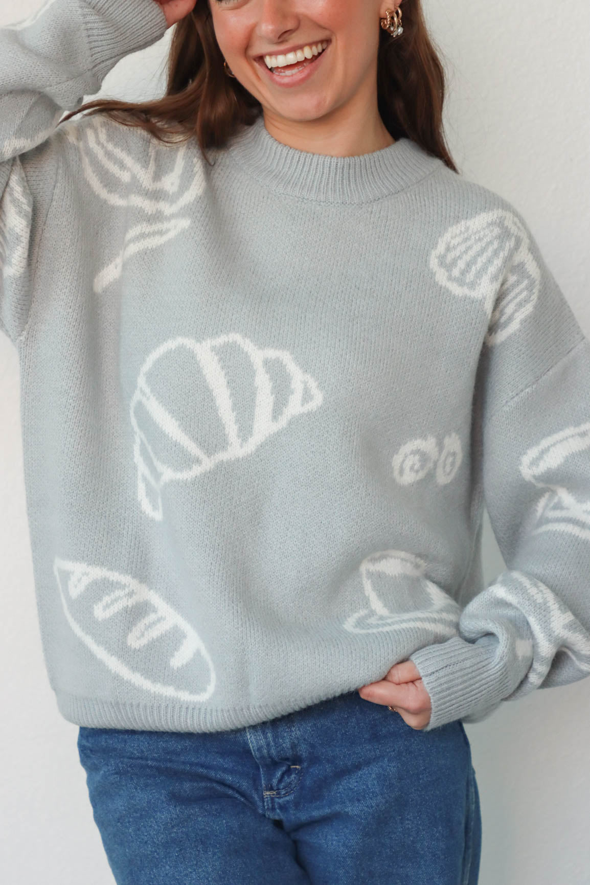 girl wearing light blue croissant and coffee sweater