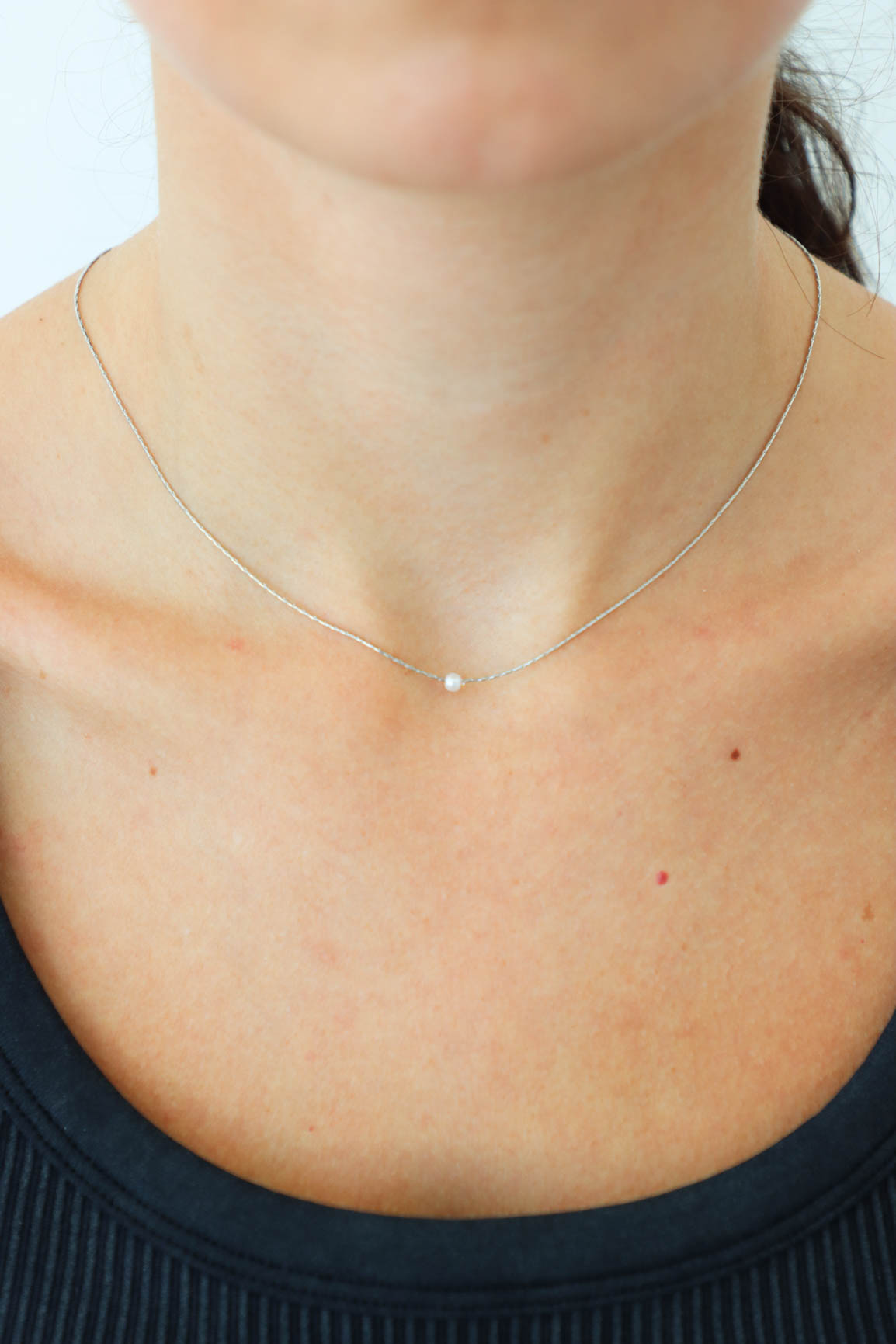 girl wearing dainty silver necklace with a pearl