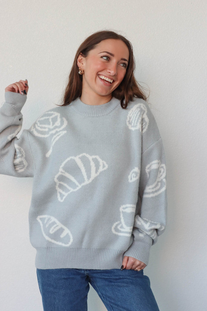 girl wearing light blue croissant and coffee sweater