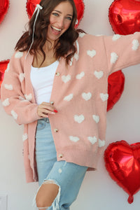 girl wearing light pink cardigan with white heart details
