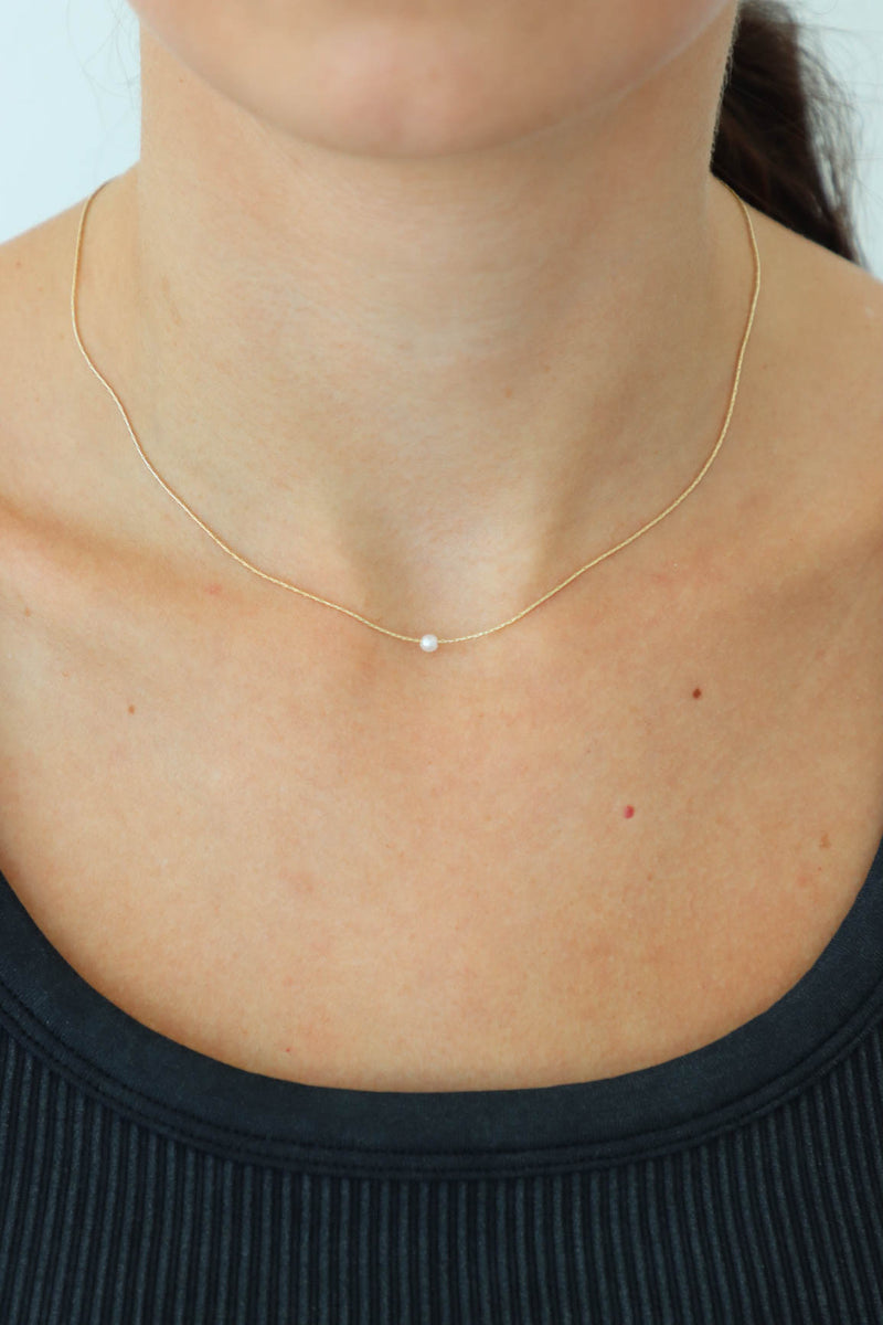 girl wearing dainty gold necklace with a pearl