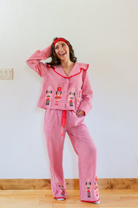 Woman wearing a red checkered pajama set with embroidered characters in a room.