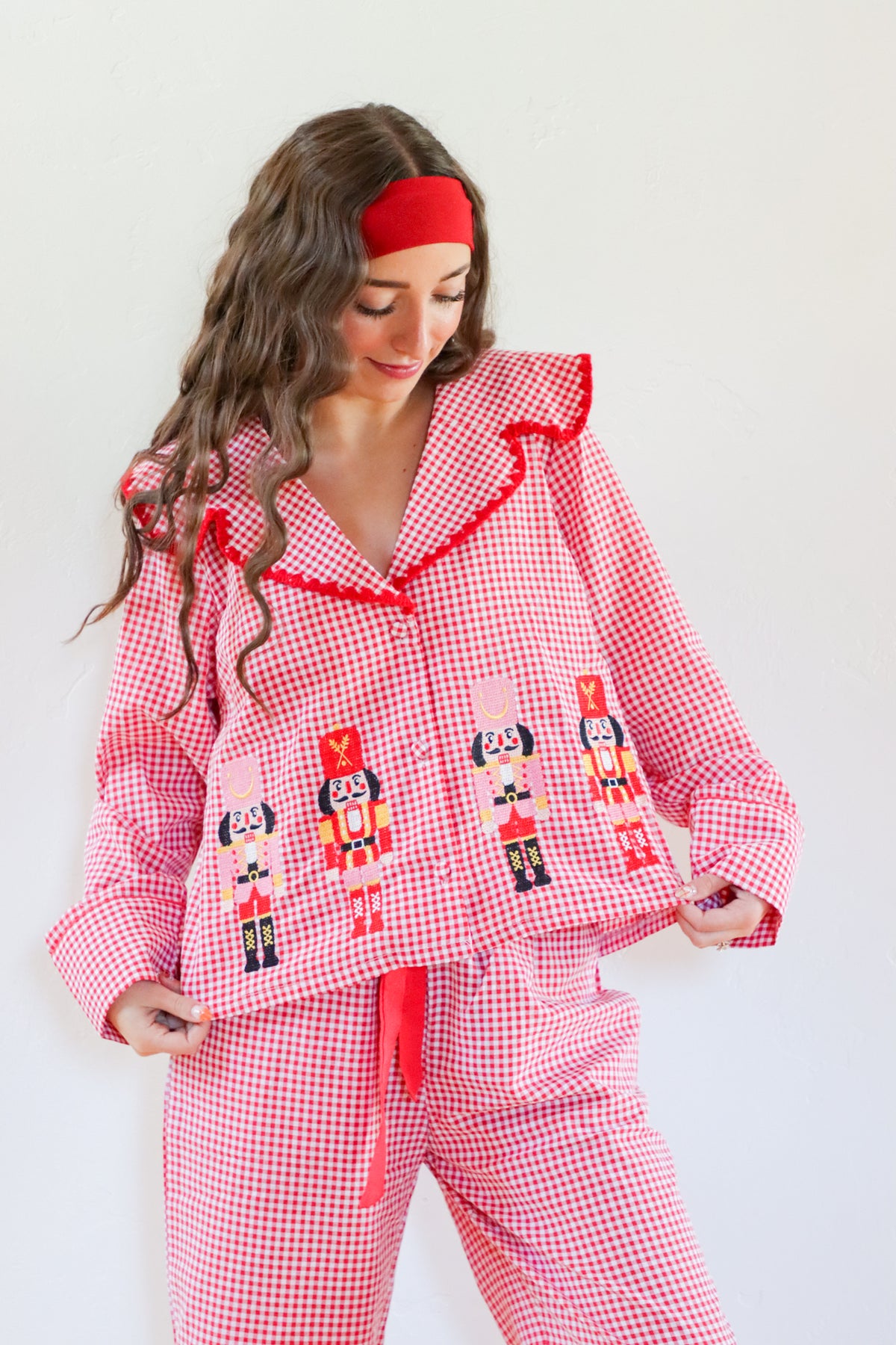 Woman wearing a red and white checkered pajama set with nutcracker design on a white background
