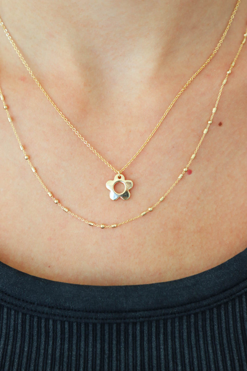 girl wearing gold flower layered necklace