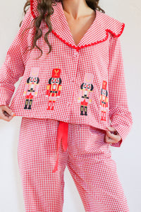 Red gingham pajama set with nutcracker design on a white background