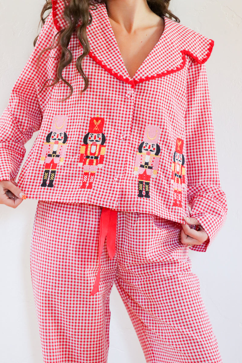 Red gingham pajama set with nutcracker design on a white background