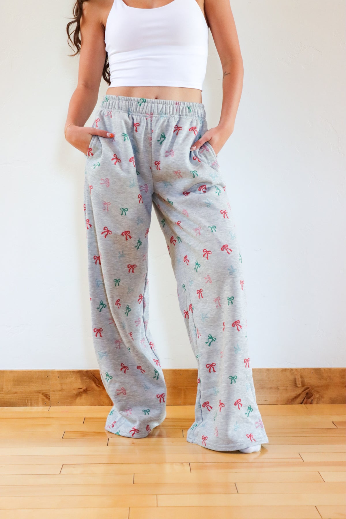 Person wearing light gray pajama pants with colorful patterns on a wooden floor.