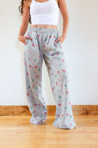 Person wearing light gray pajama pants with colorful patterns on a wooden floor.