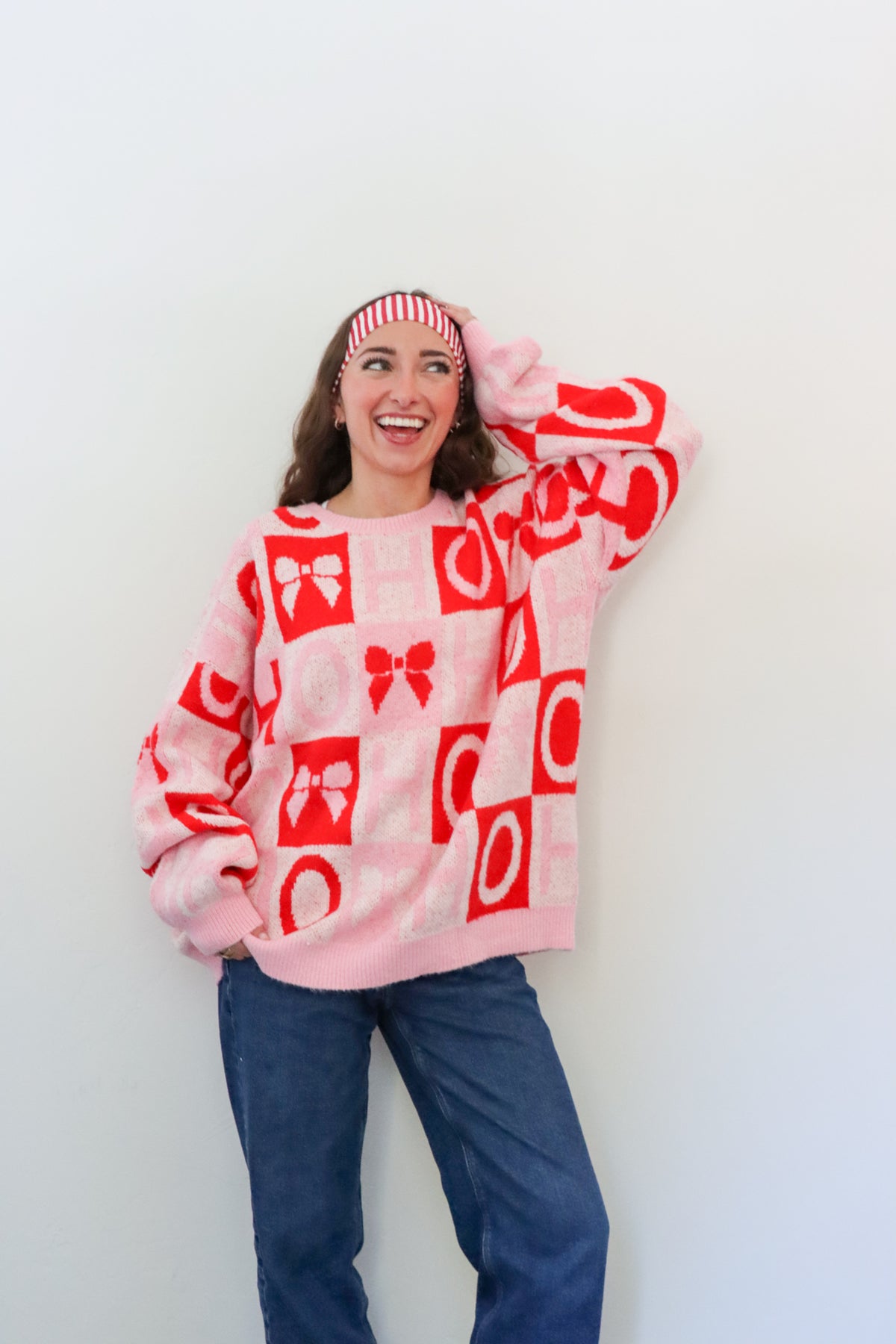 Person wearing a pink sweater with red patterns against a white background