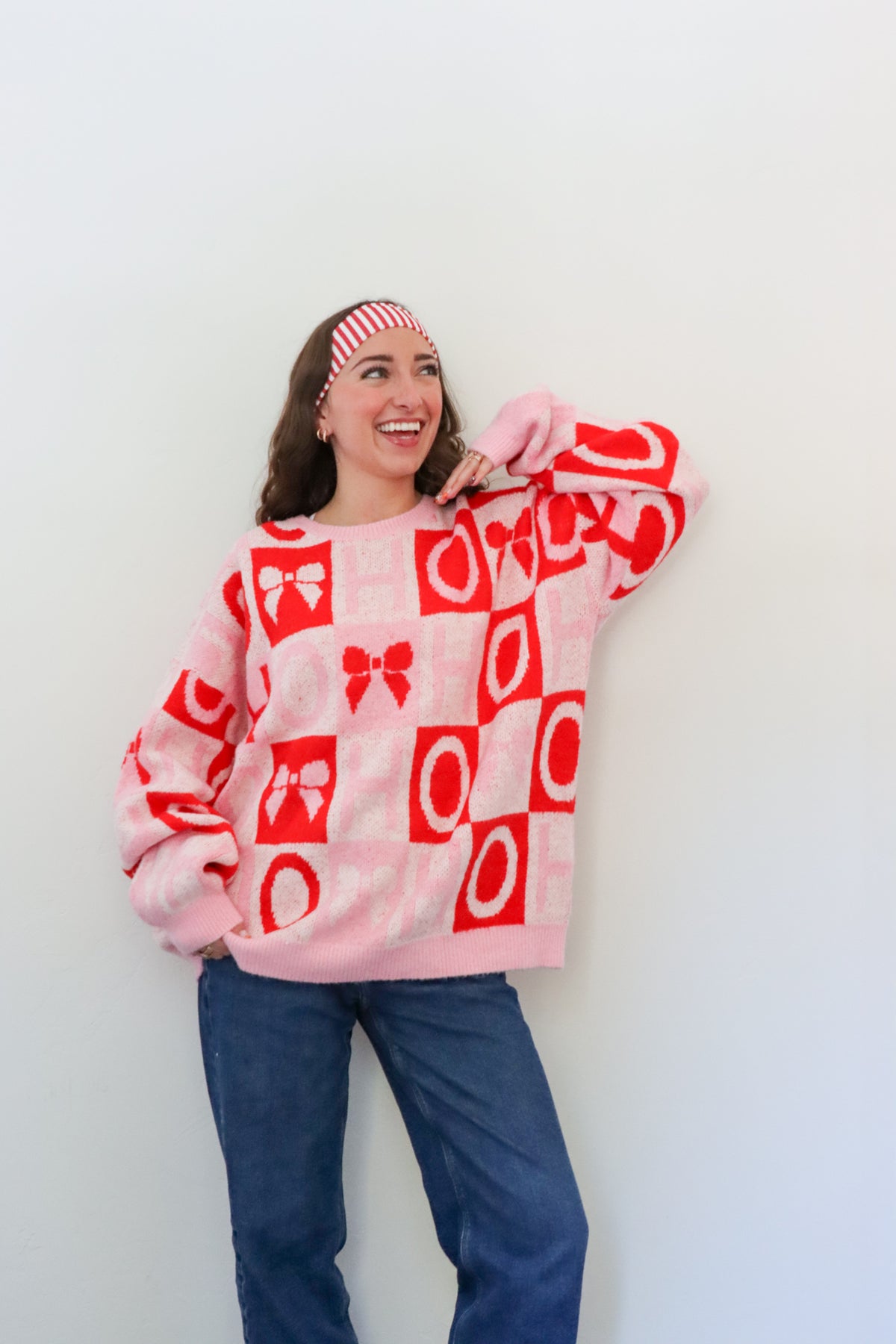Person wearing a pink sweater with red patterns against a white background