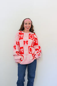 Person wearing a pink and red patterned sweater against a white background