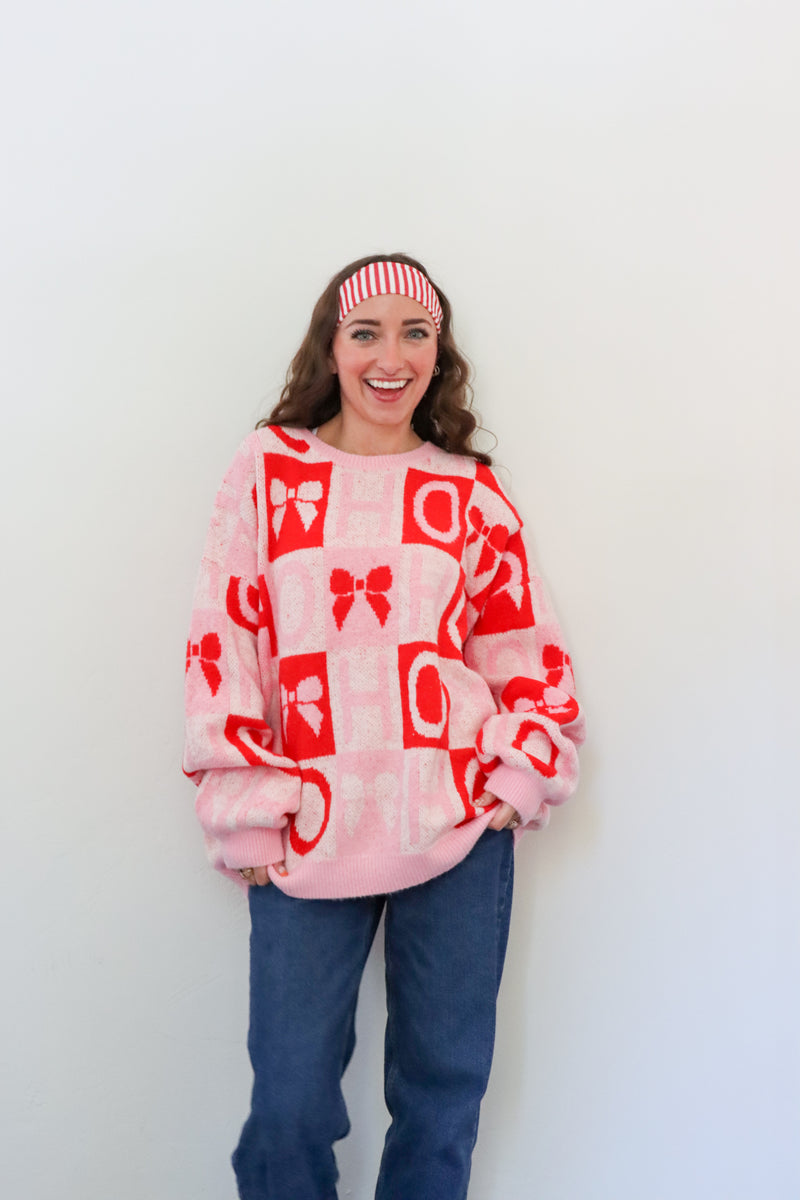 Person wearing a pink and red patterned sweater against a white background